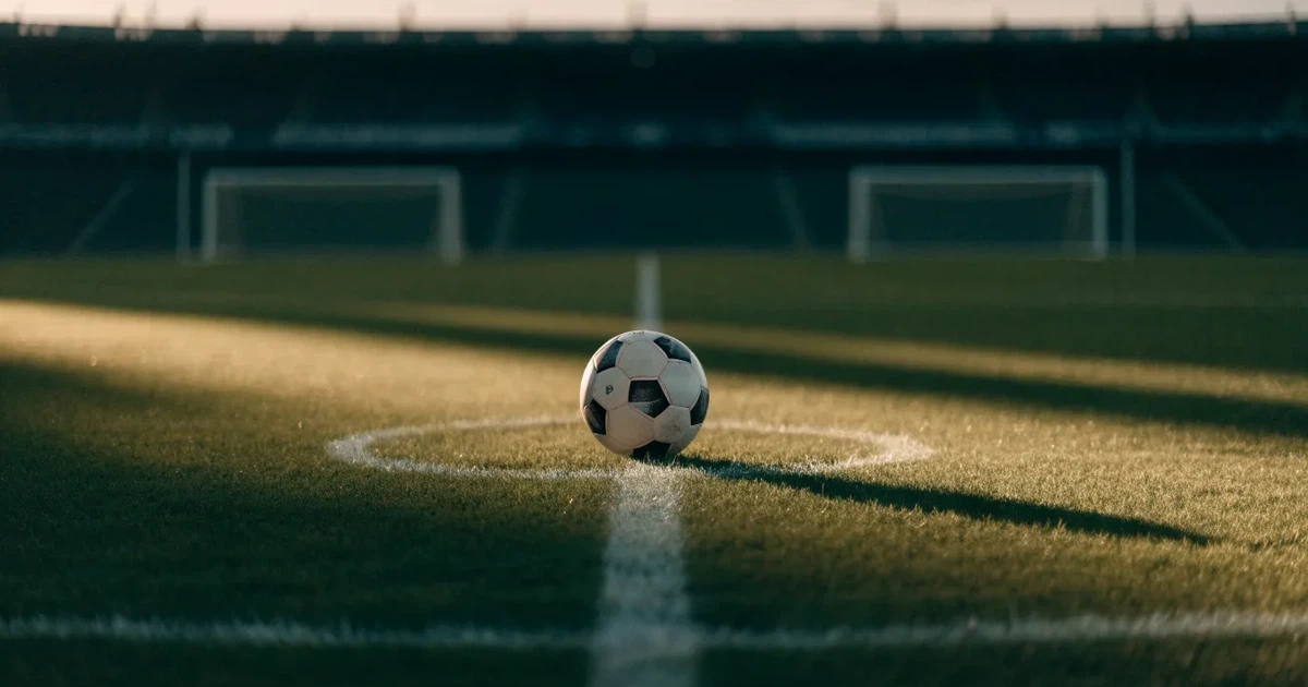 Ein Fussball liegt auf dem Mittelkreis eines Rasenfelds, die weissen Linien kreuzen sich auf dem gepflegten Gras im warmen Abendlicht.