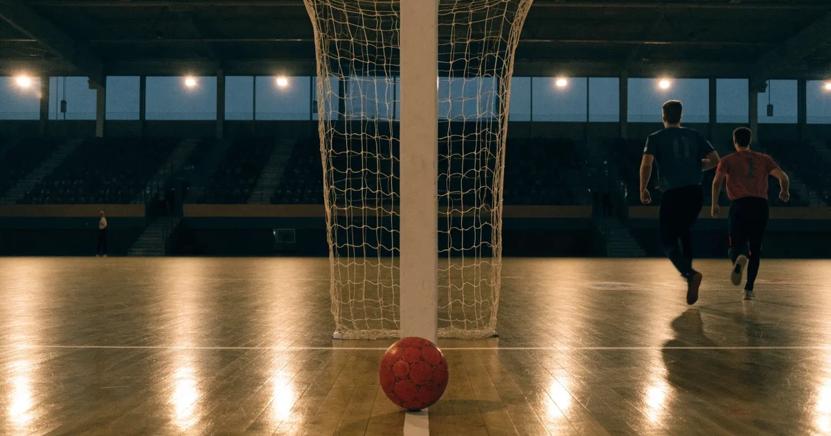 Ein Tor mit dicht gespanntem Netz steht in einer grossen Halle, davor liegt ein Handball auf der Torraumlinie.