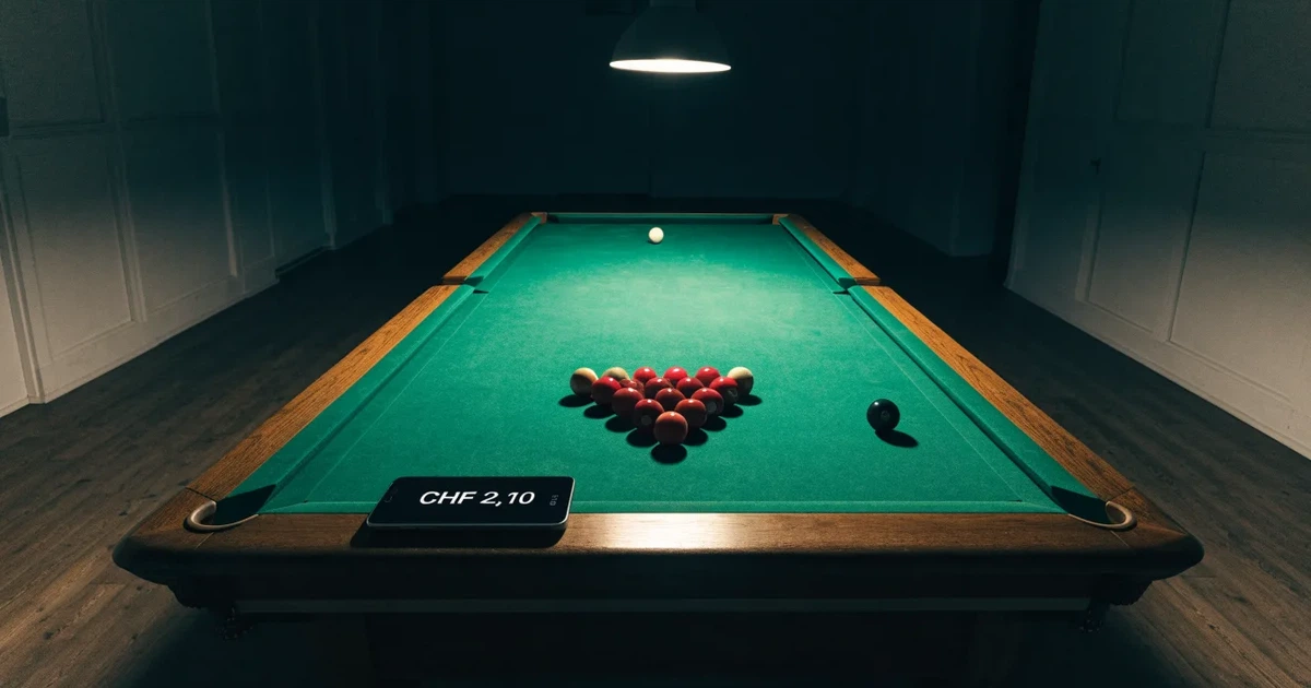 Ein Snookertisch mit grünem Tuch und einem Dreieck aus roten Kugeln unter einer tief hängenden Lampe in einer leeren Halle.